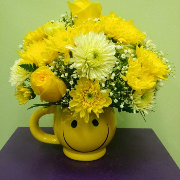 Yellow flower bouquet in a smiley-face mug vase