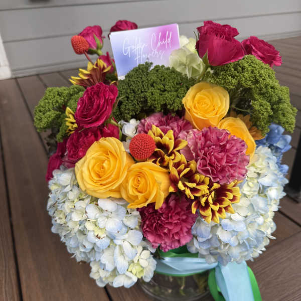 Colorful bouquet of roses, hydrangeas, and carnations in a glass vase