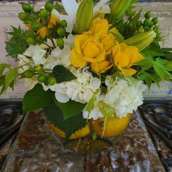 Yellow roses and white lilies in a glass vase with white hydrangeas
