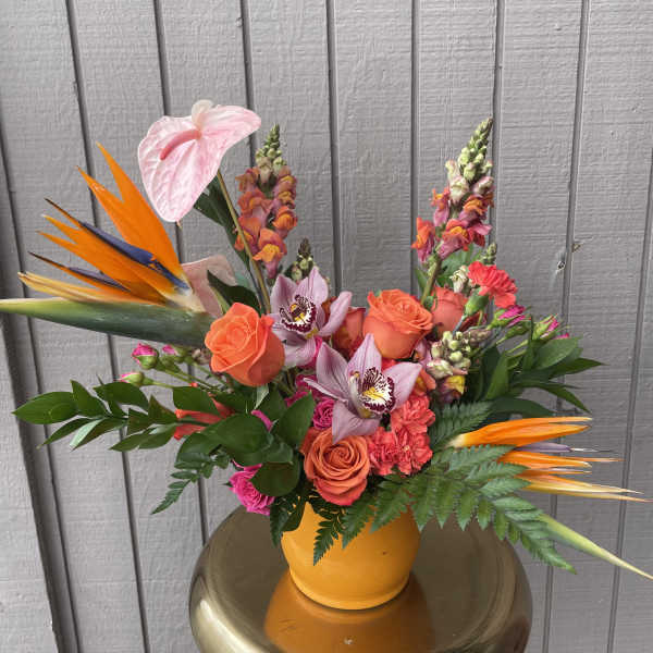Bright tropical bouquet with roses, orchids, and bird of paradise in a yellow vase