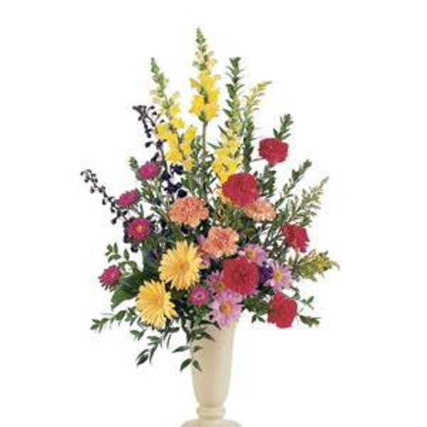 Tall mixed flower arrangement in a cream vase