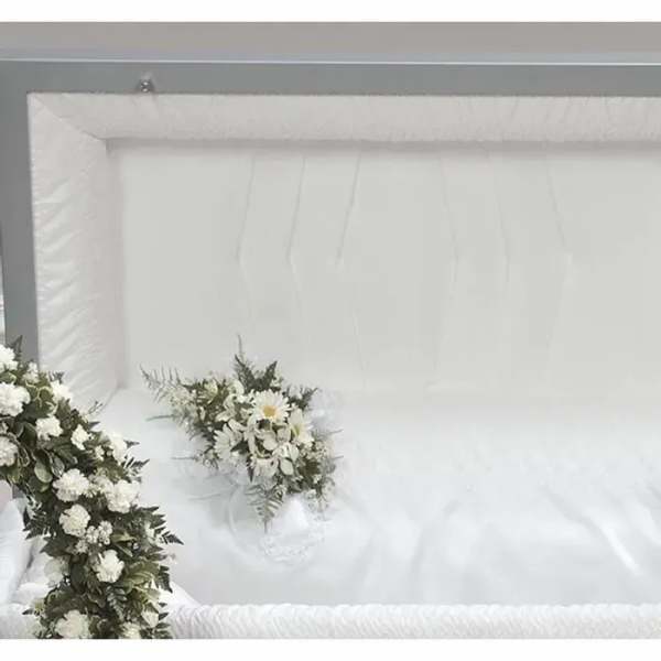 White floral arrangements in a white casket interior