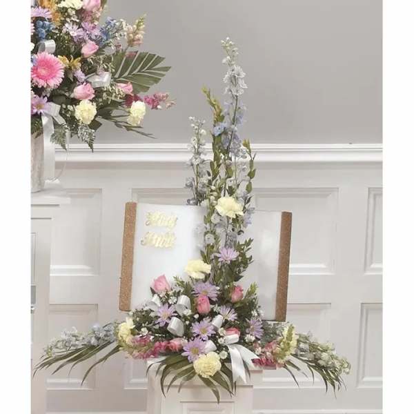 Tall pastel floral arrangement with pink, lavender, and white blooms on a pedestal.