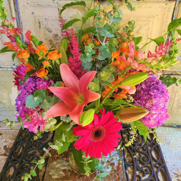 Mixed bouquet with pink lilies, gerbera daisies, and purple hydrangeas in a glass vase