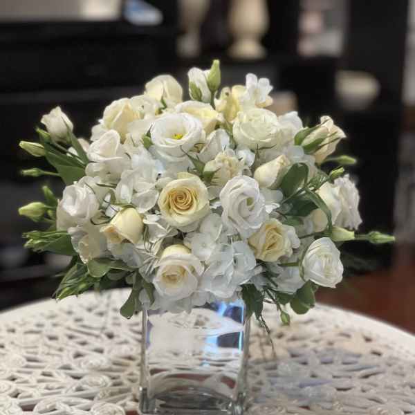 White rose and lisianthus bouquet in a clear glass vase