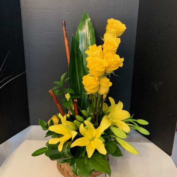 Yellow roses and lilies arranged in a basket