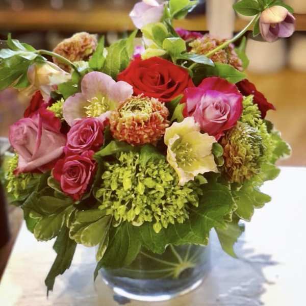 Mixed bouquet of roses and green blooms in a clear glass vase