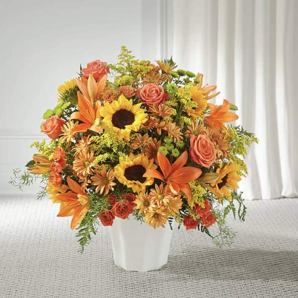 Orange and yellow mixed flower arrangement in a white vase