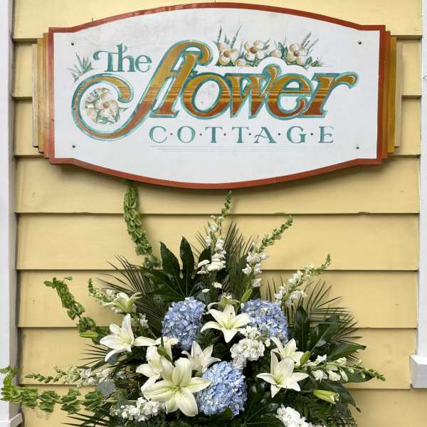 Large floral arrangement with white lilies and blue hydrangeas in a vase
