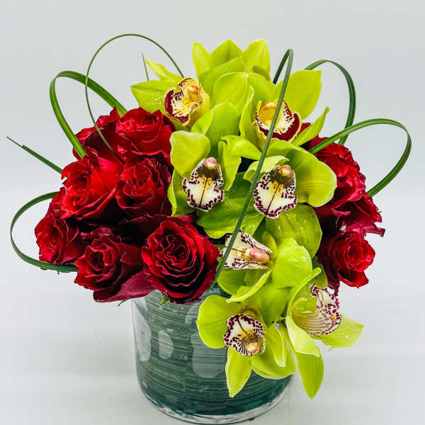 Red roses and green orchids in a glass vase