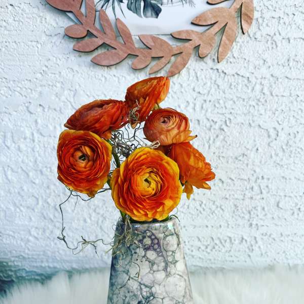 Orange ranunculus in a patterned vase