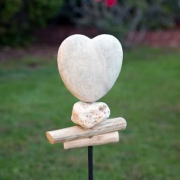 Heart-shaped stone sculpture on a metal stake outdoors
