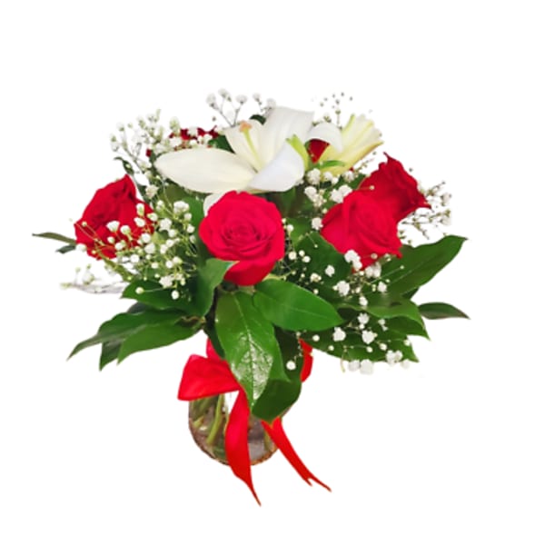 Bouquet of red roses and white lilies in a glass vase with a red ribbon
