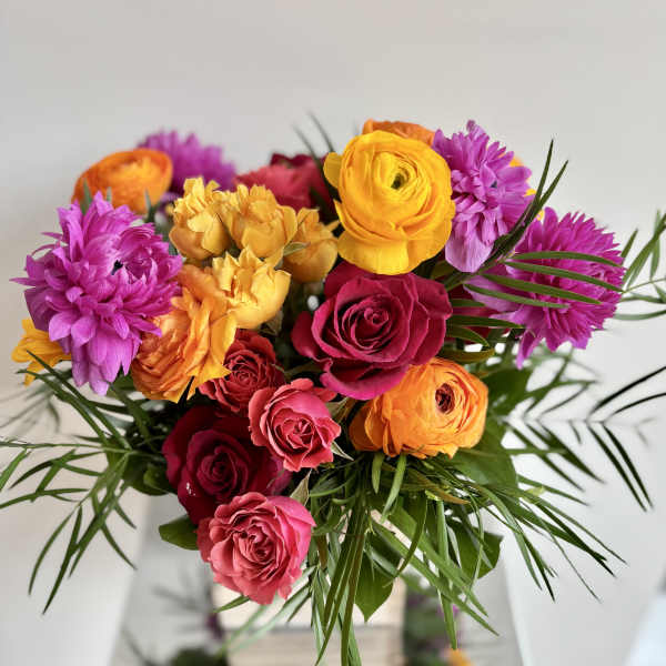 Bright bouquet of roses and purple blooms with palm-like greenery