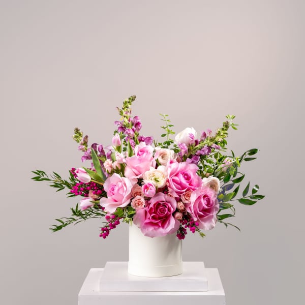 Pink and white roses arranged in a white cylindrical vase