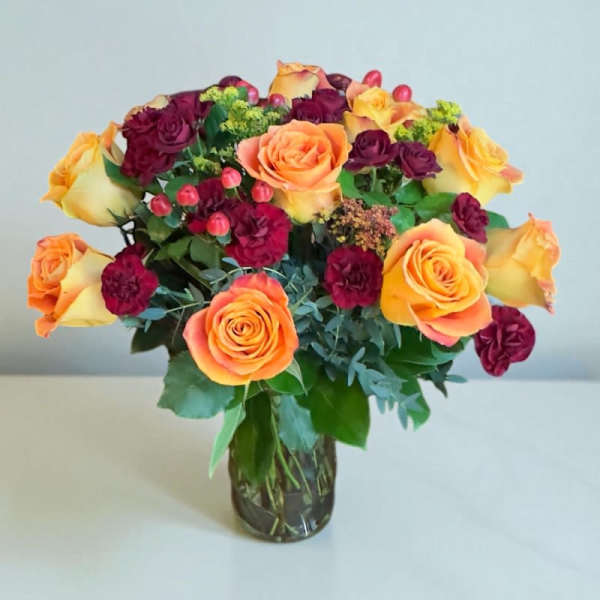Bouquet of orange and burgundy roses in a glass vase
