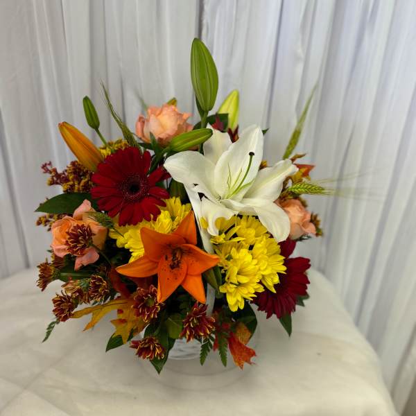 Mixed bouquet with lilies, gerbera daisies, and chrysanthemums in a clear vase