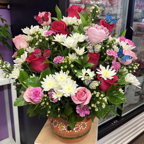 Pink and red rose bouquet with white daisies in a painted vase