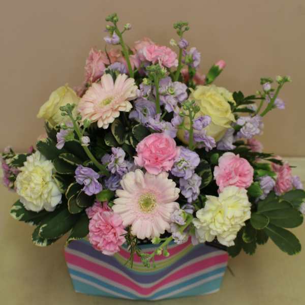 Pastel mixed flower arrangement in a striped box