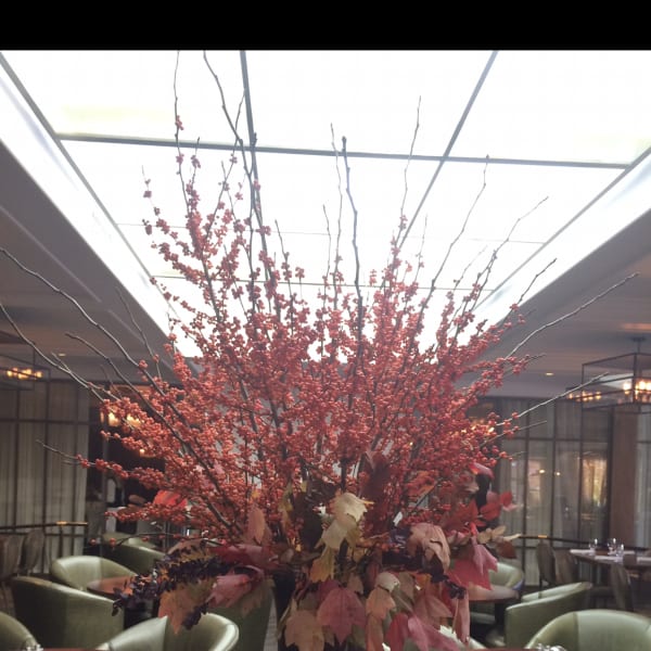 Tall red berry arrangement in a black pedestal vase