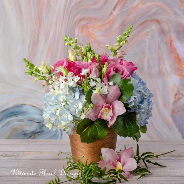 Pink roses and blue hydrangeas arranged in a copper vase