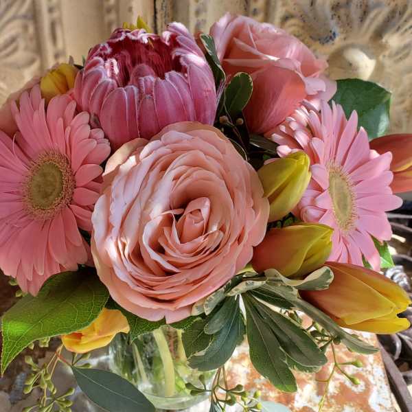 Pink mixed flower bouquet with roses, gerbera daisies, and tulips in a glass vase