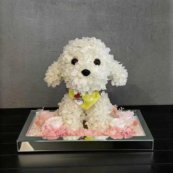 White flower-covered dog figurine in a mirrored tray with pink flowers