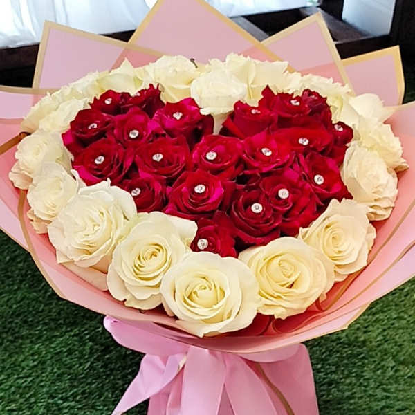 Heart-shaped bouquet of red and white roses wrapped in pink paper