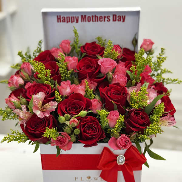 Red and pink roses in a gift box with chocolates and a red bow