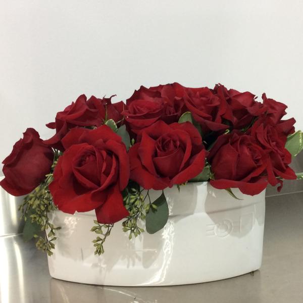 Red roses arranged in a white ceramic container