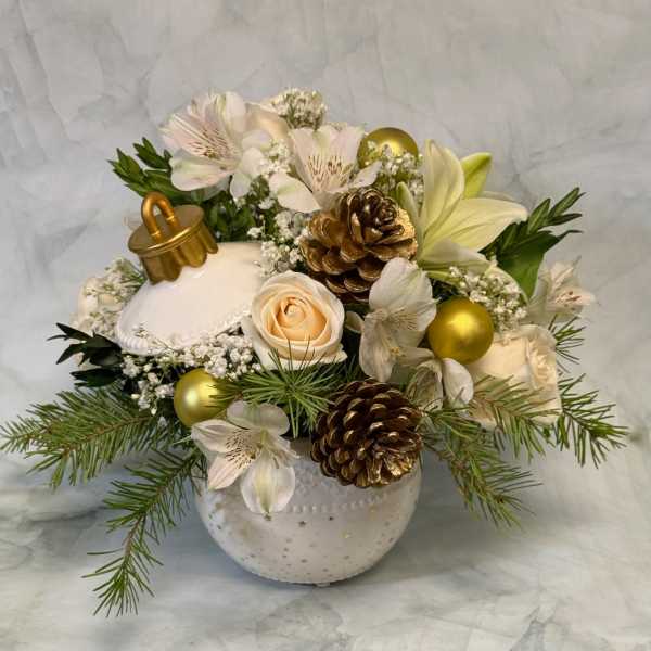 White floral arrangement with lilies, roses, pinecones, and gold ornaments in a ceramic vase