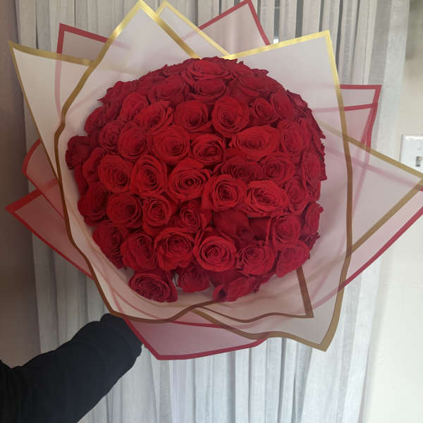 Large bouquet of red roses wrapped in pink and gold paper