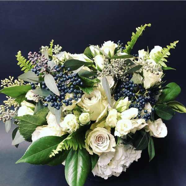 White rose bouquet with dark blue berries and green foliage