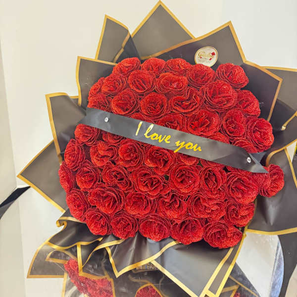 Large bouquet of red roses with a black ribbon reading "I love you"