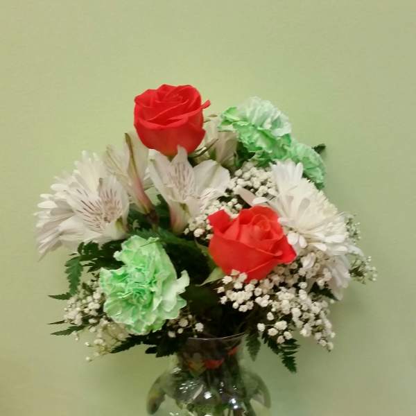 Bouquet of red roses, white daisies, and green carnations in a glass vase