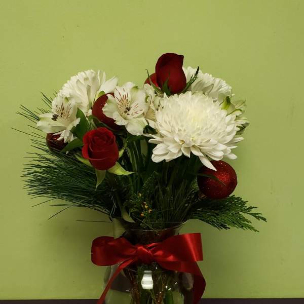 Bouquet of red roses and white flowers in a glass vase with a red ribbon