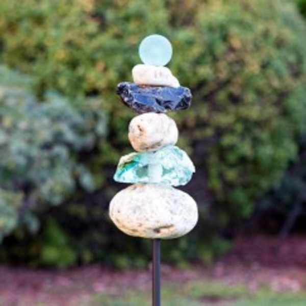 Stacked decorative stones on a metal stake in a garden