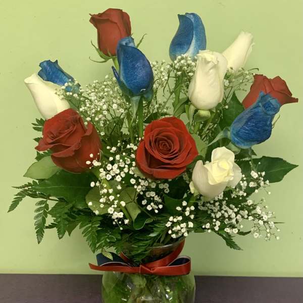 Red, white, and blue roses in a glass vase with baby's breath