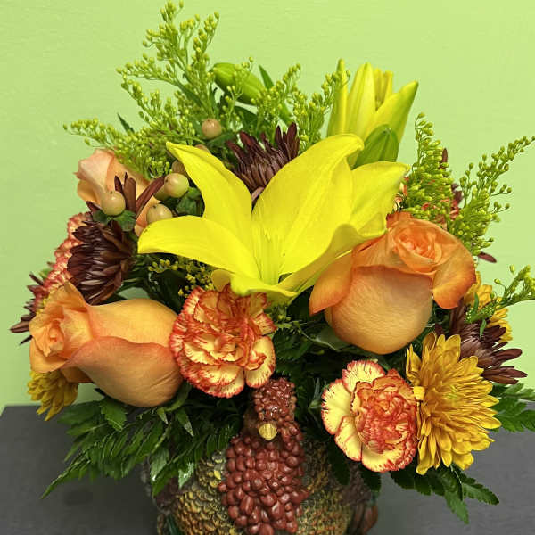 Bouquet of yellow lilies, orange roses, and carnations in a turkey-shaped container