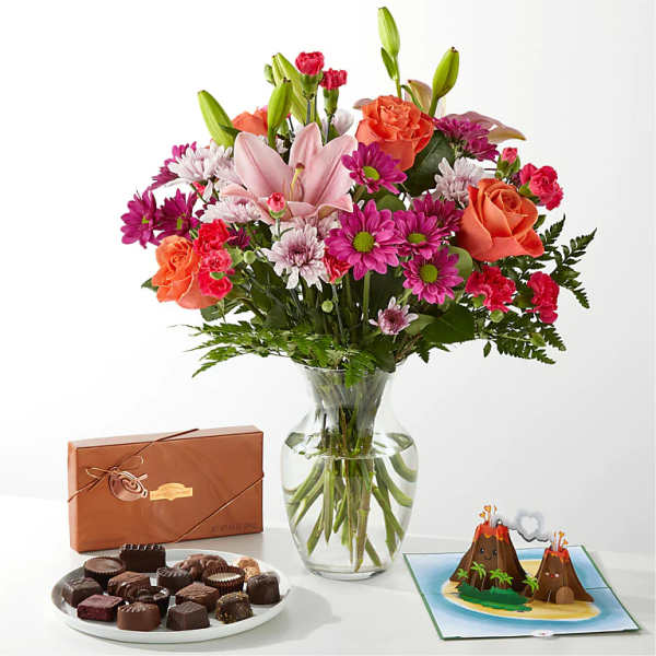Mixed bouquet in a glass vase with chocolates and a volcano card