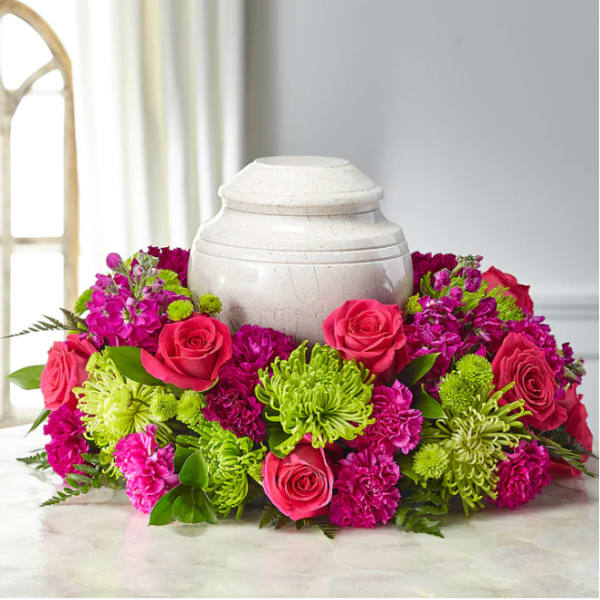 Pink roses and magenta flowers arranged around a white urn