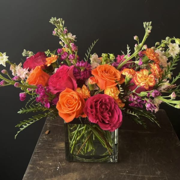 Bright mixed bouquet of orange and pink roses in a glass vase
