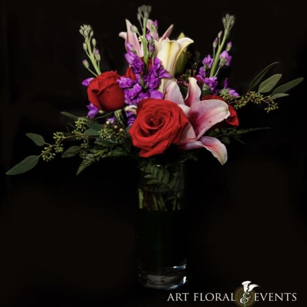 Red roses and pink lilies in a clear glass vase