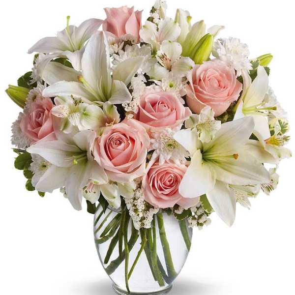 Pink roses and white lilies arranged in a clear glass vase
