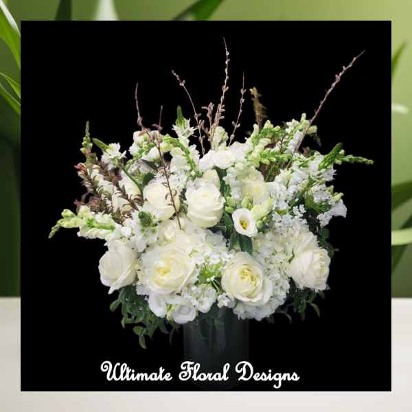 White rose arrangement in a dark vase with tall branching accents