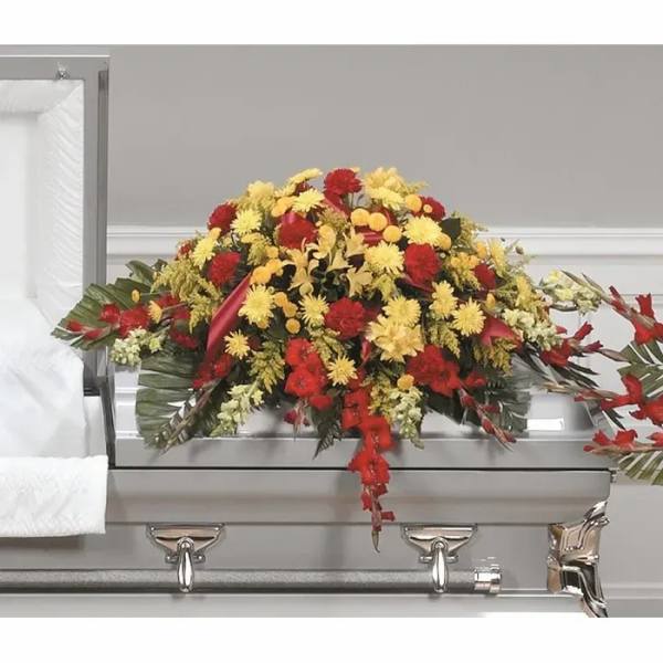 Red and yellow floral casket spray on a silver casket