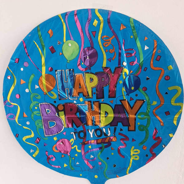 Round blue birthday balloon with colorful confetti and "Happy Birthday" text