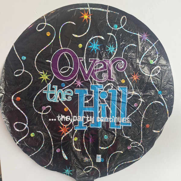 Round black foil balloon with colorful "Over the Hill" text
