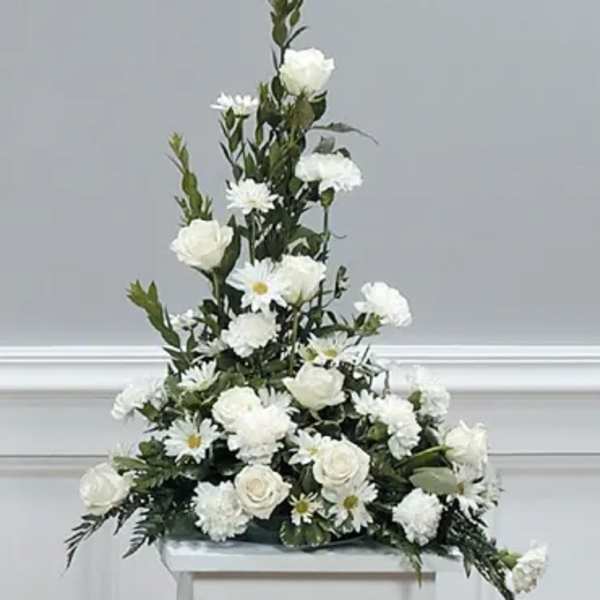 Tall white floral arrangement with roses and daisies on a stand