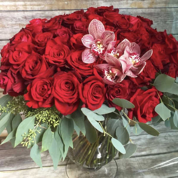 Red rose bouquet with pink orchids in a glass vase